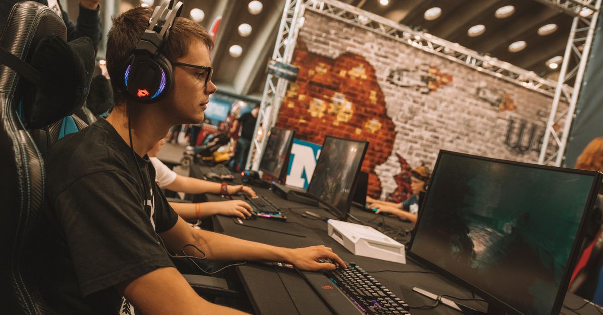 A young male gamer intensely focused during an esports event at an indoor gaming convention.